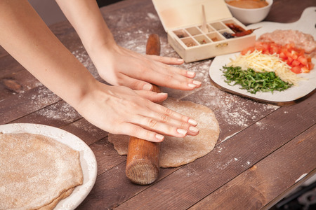 women hands chef rolling pastry for tacos on wooden tableの写真素材
