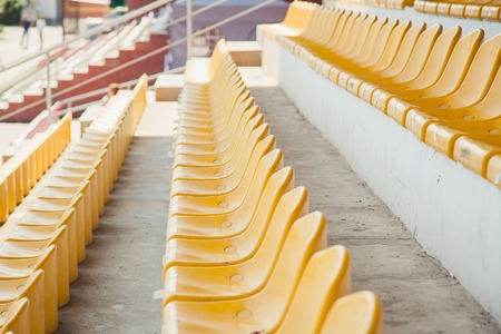 row of empty yellow plastic chairs at stadium.の写真素材