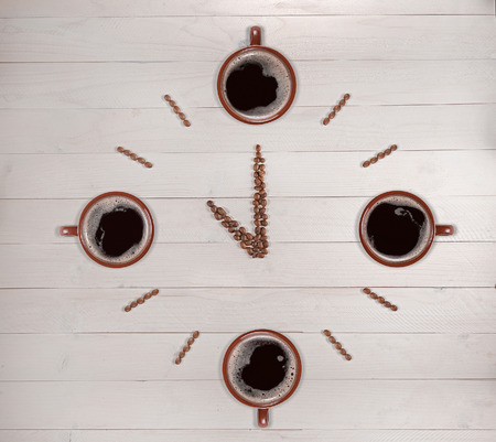 Clock made of coffee beans and cups on wooden background.の写真素材