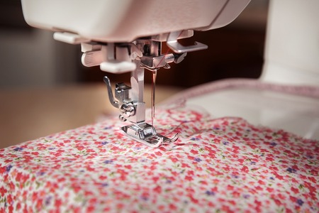 Closeup of needle sewing machine with pink tissue.