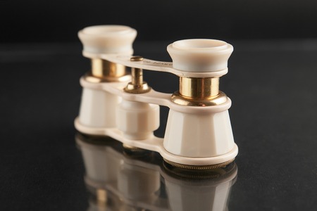 ivory opera glasses on dark mirror background.の写真素材