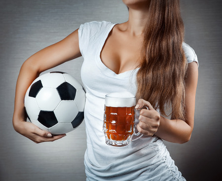 young sexy woman holding soccer ball and beer mug. Open breast. Closeup.の写真素材