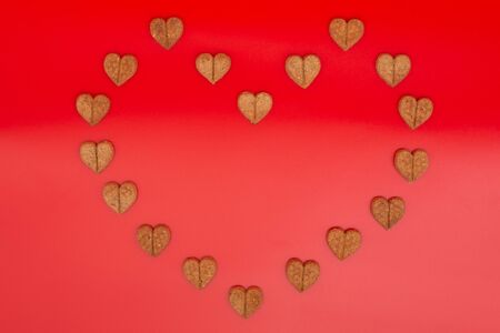 Heart shaped biscuits arranged in heart shape on red backgroundの写真素材