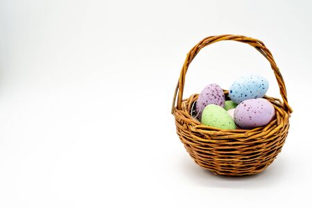 Mini woven easter basket with coloured speckled eggs isolated on white backgroundの写真素材