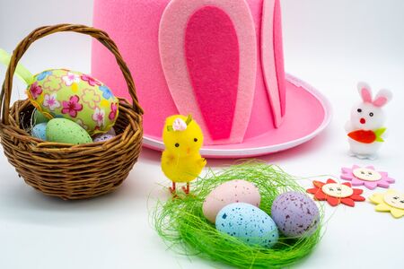 Collection of craft items for making easter projects including a pink hat, mini woven basket, white...