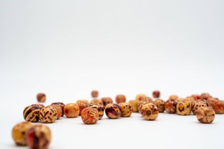 Scattered wooden decorated beads for craft. Macrame beads. Animal print patterns. Shot from low angle.Isolated on white background.の写真素材