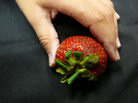 Fingers picking up strawberry.の写真素材