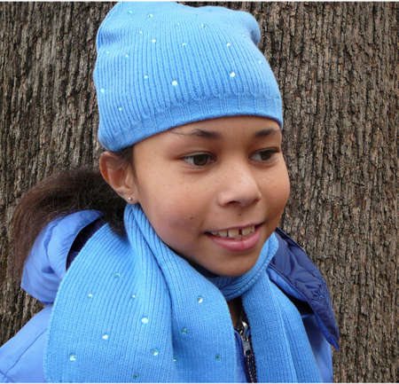 Child all bundled up and standing by treeの写真素材