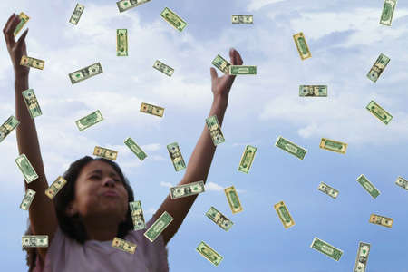 Child collecting money as it falls.の写真素材