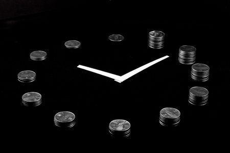 A clock on black background made from silver coin towers showing concept of loosing money as time goesの写真素材