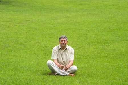 Smiling man sitting on grass fieldの写真素材