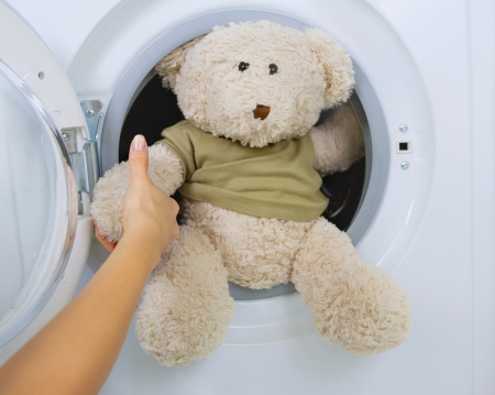 woman taking fluffy toy from washing machineの写真素材