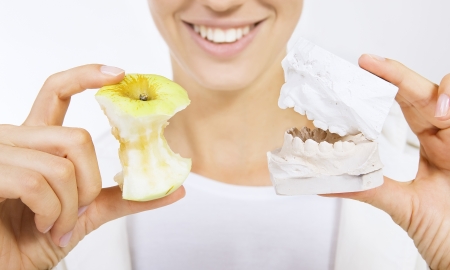 Woman holding a teeth sample and apple