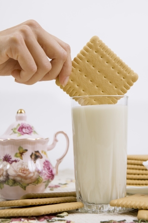 A person dunking a cookie in a glass of buttermilk (milk)の写真素材