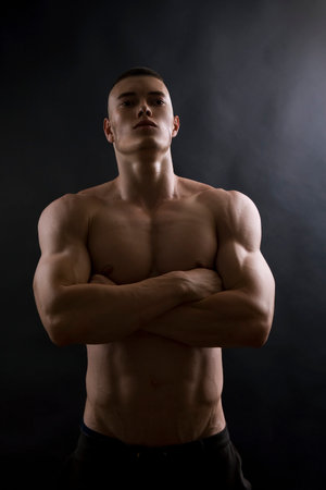 Young sexy man with athletic body posing on black background.のeditorial素材