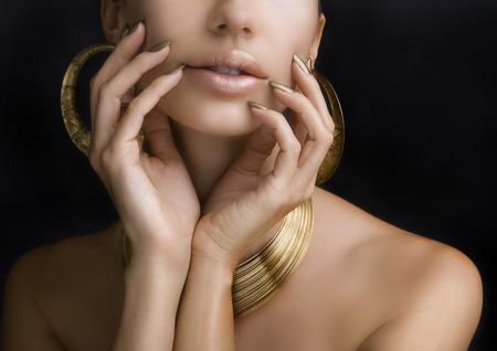 Beautiful Women Lips with Stylish Golden Shiny Lipstick and Hands with Golden Manicure and Gold...