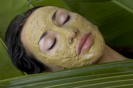 Spa Outdoor, Beautiful young woman lying with natural green herbal clay facial mask on her face, skin care and wellnessの写真素材