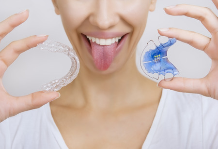 Beautiful Smiling girl Holding Retainer for Teeth (Dental Braces) and Individual Tooth Tray....