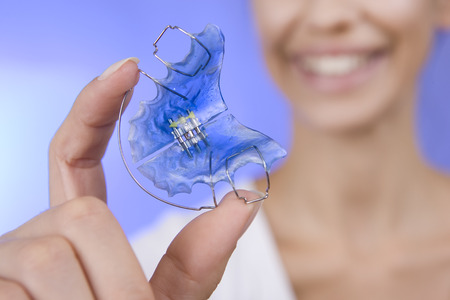 Beautiful Smiling Girl Holding blue Retainer, Braces for Teeth. Orthodontics Dental Theme, Methods...