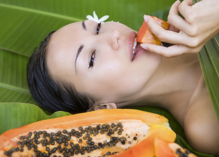 Beautiful caucasian woman with fresh fruit papaya (outdoors). Healthy Natural Exotic Food, Luxury Rest in the Tropical countries of Asiaの写真素材