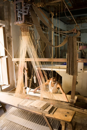 VARANASI, INDIA, DEC 9: Unidentified man makes a traditional sari cloth, hand loom on old fabric factory on Dec 9, 2013, Varanasi, India. Textile industry in Varanasi preserved ancient traditionsのeditorial素材