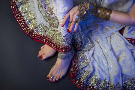 Indian Wedding Preparation. Luxury Oriental Fashion beauty Accessories: Female foot, Beautiful National Indian Bridal Golden Jewellery. Eastern Traditional Sari clothes. Blue filter, dark backgroundの写真素材