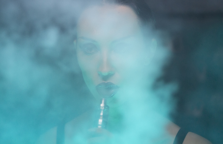 Club Party â Nightlife. Beautiful Sexy Young Glamorous Woman Relaxing in the Chill-out in Nightclub and Smoking Hookah and exhaling smoke. Chilling. Sensual Girl at the bar. Disco illuminatedの写真素材