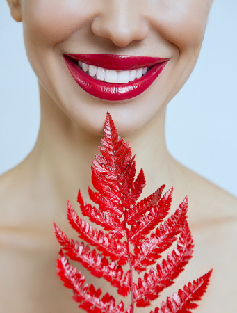 Smile with healthy tooth. A woman with red lips and a fern. Woman's mouth with Sexy red Lips. Female portrait with bright Lip gloss.
Dental conceptの写真素材