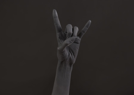 Goat gesture on a dark background. Black hand doing rock symbol. Hands up at a rock concert. Music...