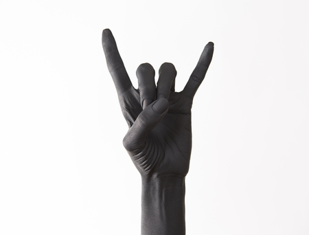 Goat gesture on a dark background. Black hand doing rock symbol. Hands up at a rock concert. Music star. Heavy metal concept. Black metal.の写真素材