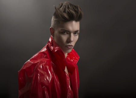 Young man's portrait. Stylish handsome sexy Guy in fashionable red Long lacquer raincoat, Close-up...