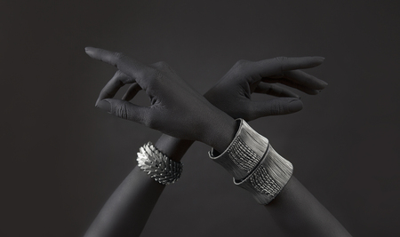 Black woman's hands with many different Silver jewelry. Oriental Bracelets on a black hand. Silver Jewelry and luxury accessories on black background. High Fashion art conceptの写真素材