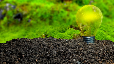 Glowing light bulb on green moss background with copy space. Eco concept