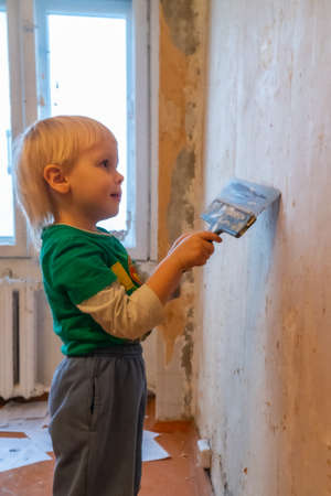 The boy helps to make repairs in the apartmentの写真素材