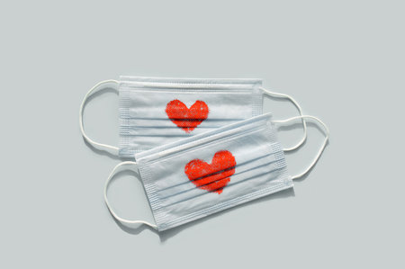medical protective mask with red hearts on a blue background. The concept of a healthy protected...