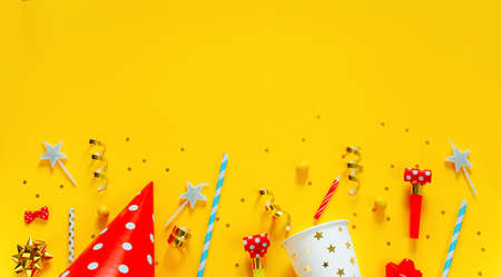 Happy birthday background: party hat, serpentine, stars, cocktail tubes, candles, blower on a yellow background.の写真素材