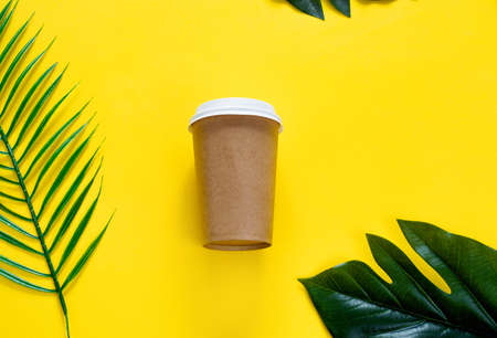 Eco friendly paper glass, cocktail tubes, tropical leaves on yellow background. Zero waste, plastic free concept.の写真素材
