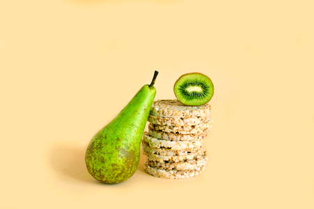 Fitness crispbread, pear, kiwi, on a beige pastel background.Copy space.Vegetarian, alkaline food concept. Healthy eating.の写真素材