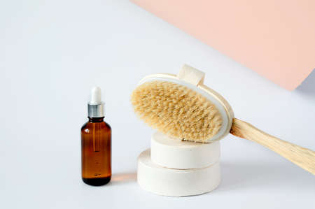 Wooden massage brush for dry, anti-cellulite massage and body oil on a concrete podium on a white background.の写真素材