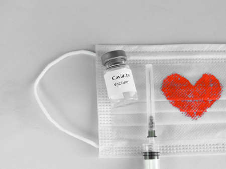 Coronavirus vaccine COVID-19, medical mask, syringe, on a grey background close-up. Vaccine Concept...