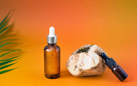 Various glass vials with face serum on a stone concrete podium and branches with flowers. Organic...