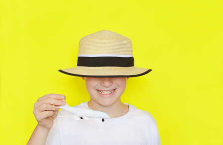 Happy smiling 9 year old Caucasian boy in a straw hat and holds a spinning plane in his hands on a...