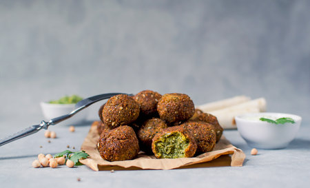 Fresh falafel balls on a black gray background with yoghurt sauce.