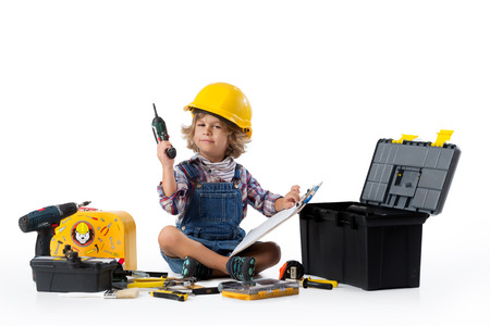 Little boy dressed as utility worker with protective helmet trying to figure ou how the drill worksの写真素材