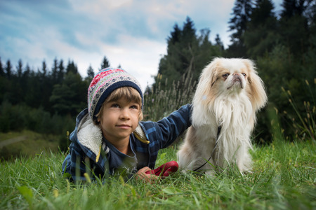 Cute little boy lying on the grass next to his dog. Best friends concept.の写真素材