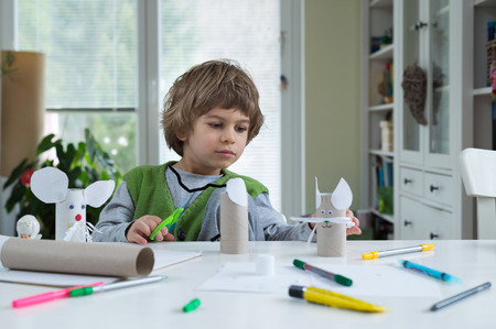 Little boy being creative making homemade diy paper toys. Supporting creativity, learning by doing,...