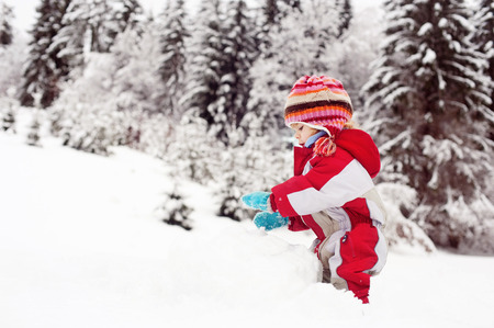 Little boy dressed in winter clothes having fun outside in the snow.の写真素材