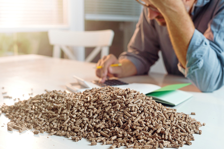 Man calculating household heating costs. Wooden pellets, biomass, effective, environmentally friendly and economical heating, sustainable and renewable energyの写真素材