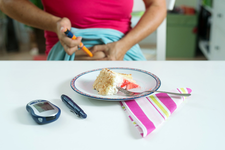Female diabetic patient injecting herself with shot of insulin before having a piece of cake for desert.の写真素材