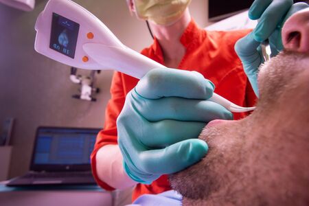 Automatic Digital Periodontitis detector being used on patients teeth for diagnosing periodontal status and diseases  Digital dentistry, modern technology, oral hygiene.の写真素材